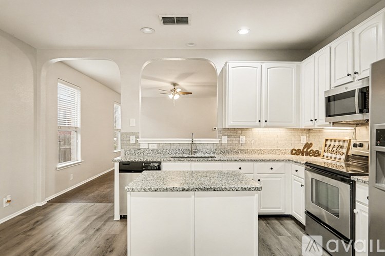 A kitchen with white cabinets and a granite countertop.