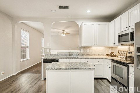 A kitchen with white cabinets and a granite countertop.