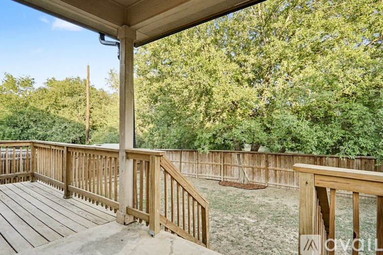 A wooden deck with a railing and steps leading to a covered area.