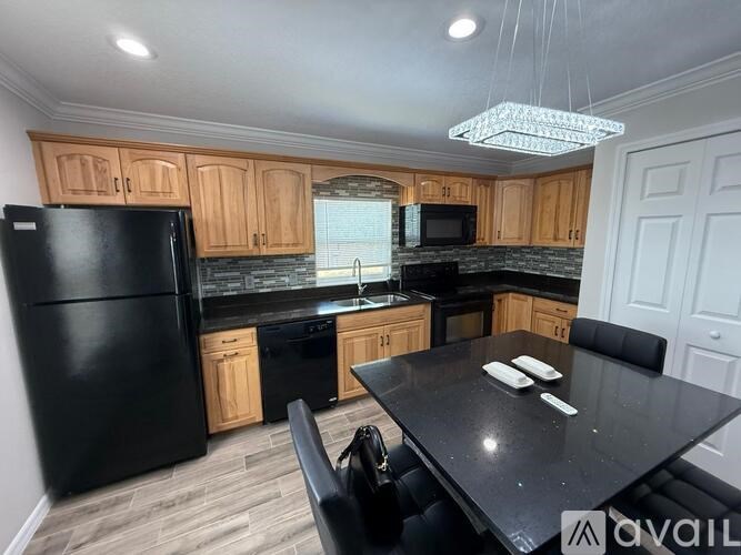 A kitchen with black appliances and wooden cabinets.