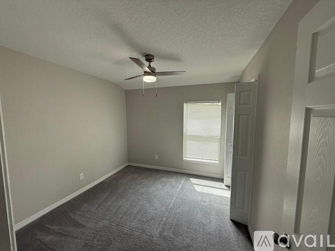 A room with a ceiling fan and carpeted floor.