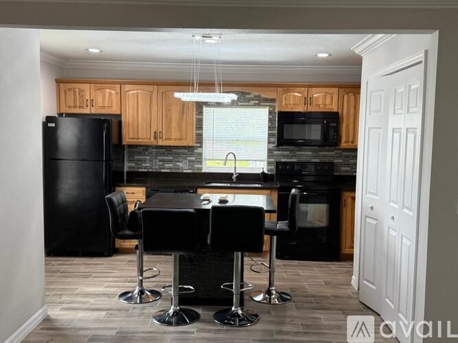 A kitchen with black appliances and a black table with four stools.