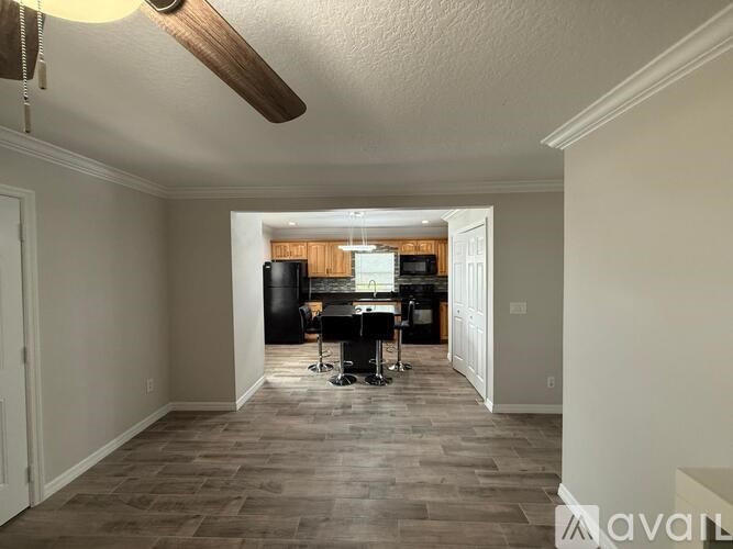 A room with a kitchen area in the background and a dining table with chairs in the foreground.