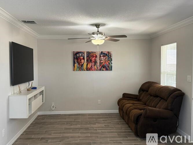 A living room with a brown couch and a painting on the wall.