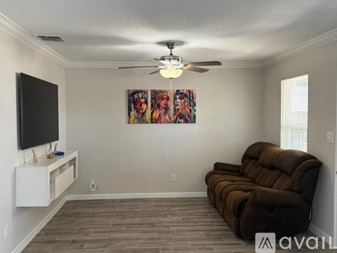A living room with a brown couch and a painting on the wall.
