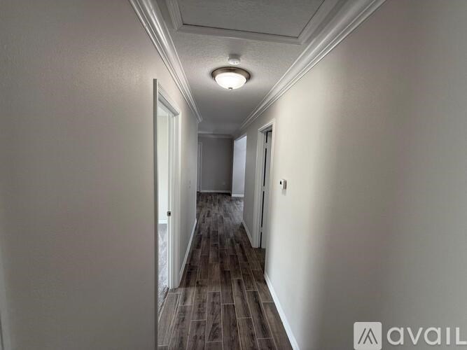 A long hallway with wood flooring and white walls.