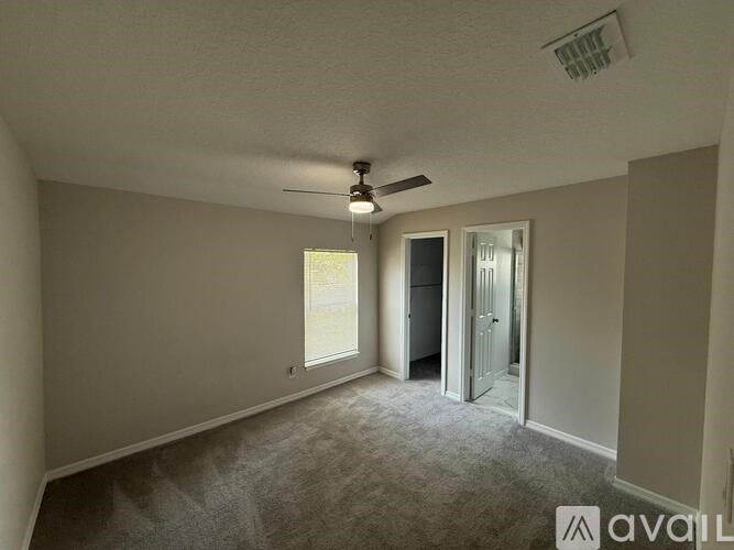 A room with a carpeted floor and a ceiling fan.