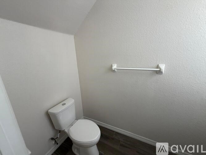 A white toilet in a small bathroom with a towel bar on the wall.