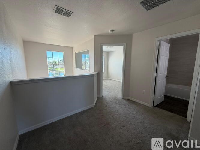 A room with a carpeted floor and a window with a view of a parking lot.