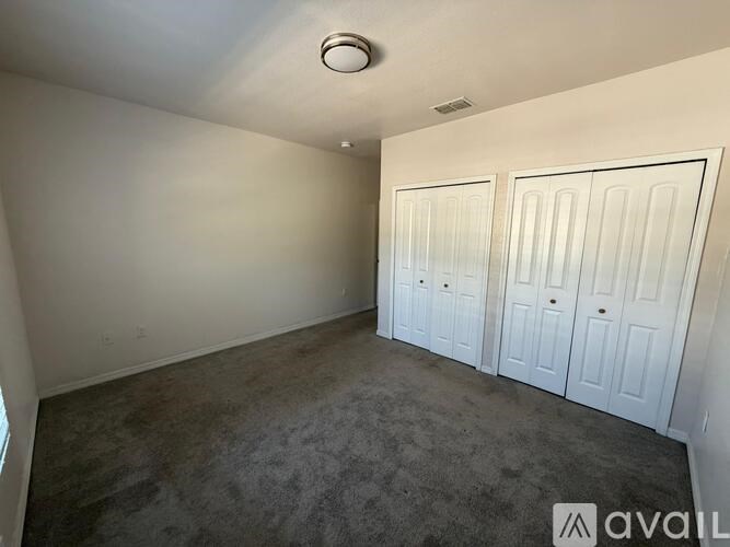 A room with white doors and carpeted floor.