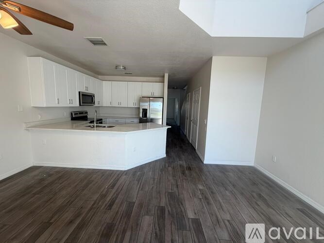 A spacious living room with a kitchen area in the background.
