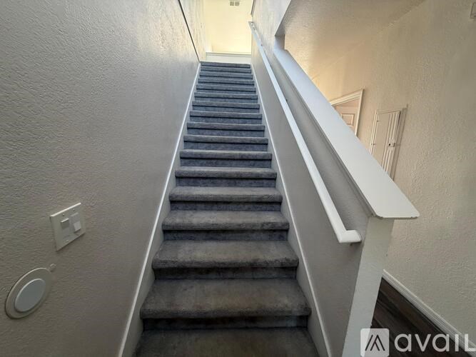 A staircase with a carpeted runner and white handrails.