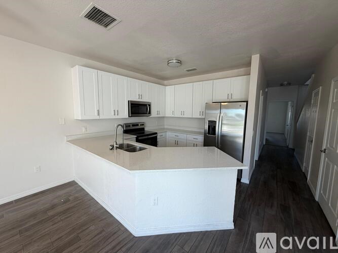 A kitchen with white cabinets and a wooden floor.