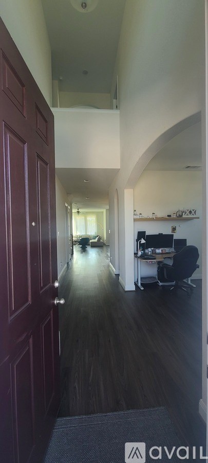A hallway with a red door and a black chair.