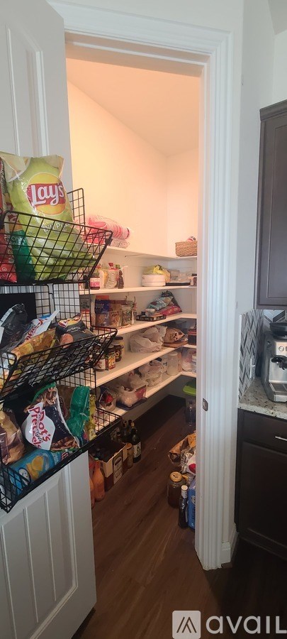 A small, white doorway leads to a small kitchen with a refrigerator.