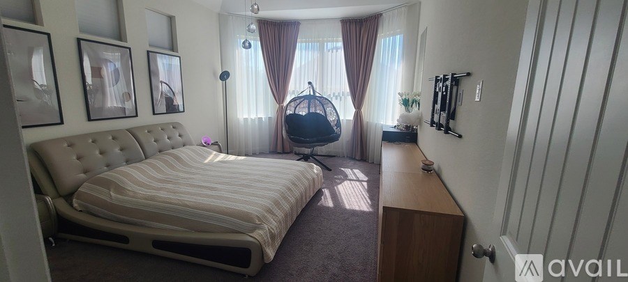 A bedroom with a large bed and a hanging chair.