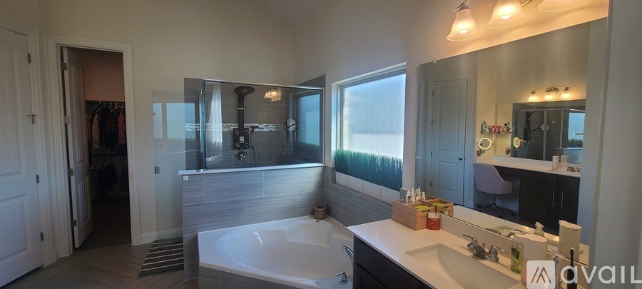 A bathroom with a tub, sink, mirror, and a window.