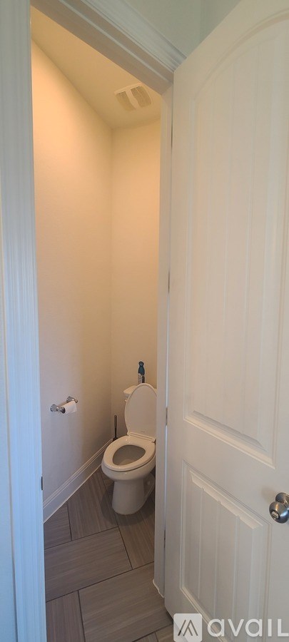 A white door is open to a small bathroom with a toilet.