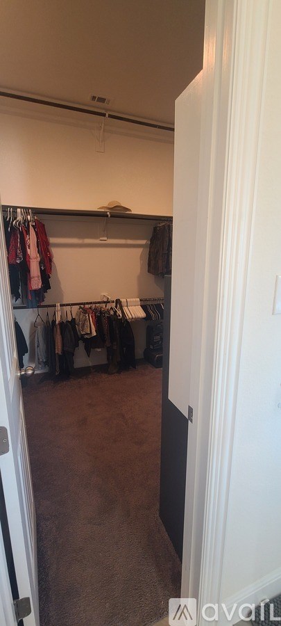 A room with a white door and a wall with clothes hanging on it.