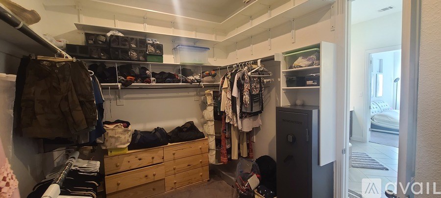 A small, white-walled room with a bunk bed and a closet full of clothes.