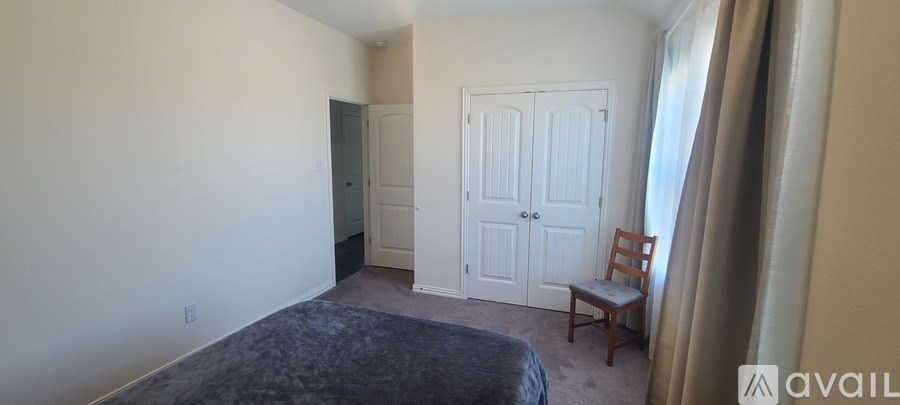 A bedroom with a bed, chair, and two doors.