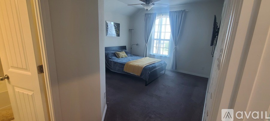 A bedroom with a bed, a ceiling fan, and a window with curtains.