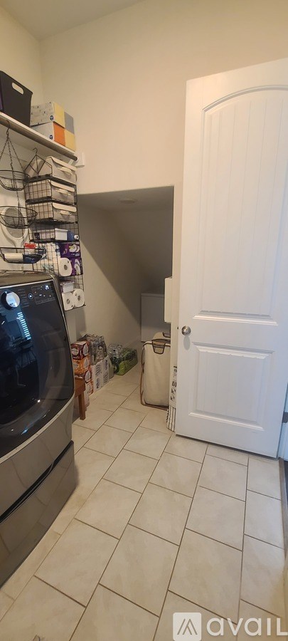 A kitchen with a white door and a white tiled floor.