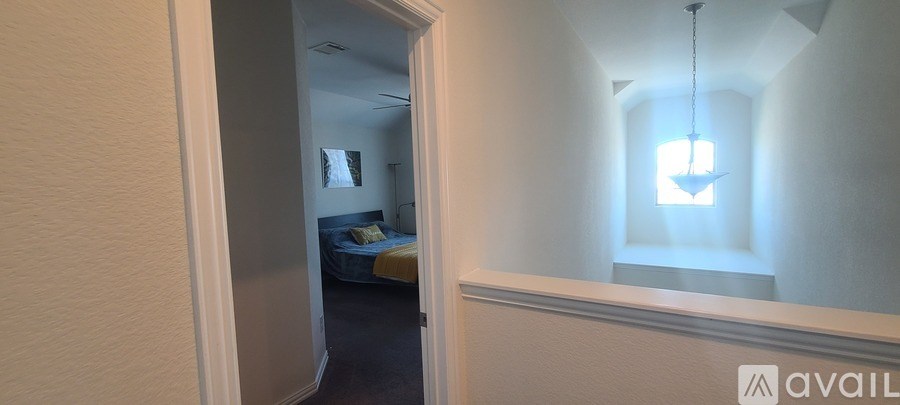A bedroom with a bed and a hanging light fixture.