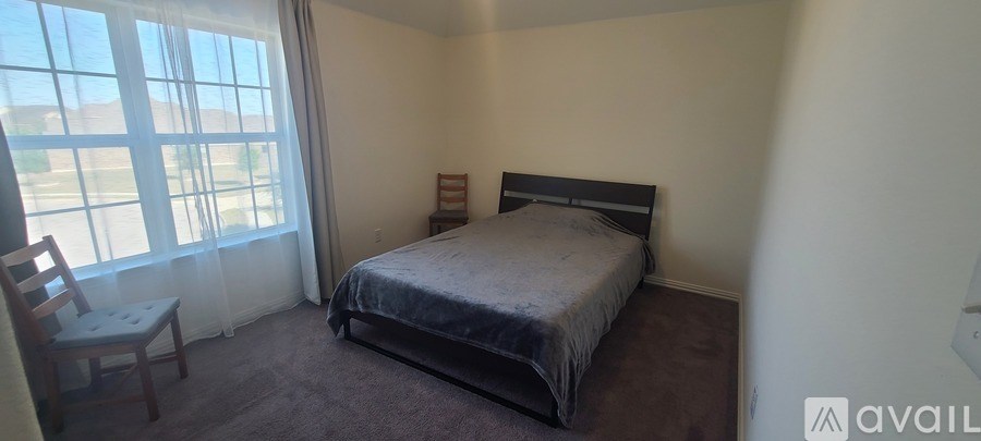 A bedroom with a bed, chair, and window.