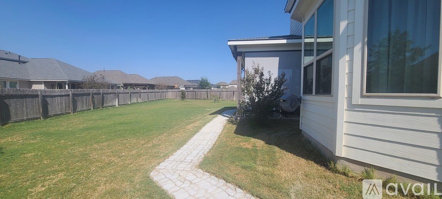 A white house with a backyard and a fence.