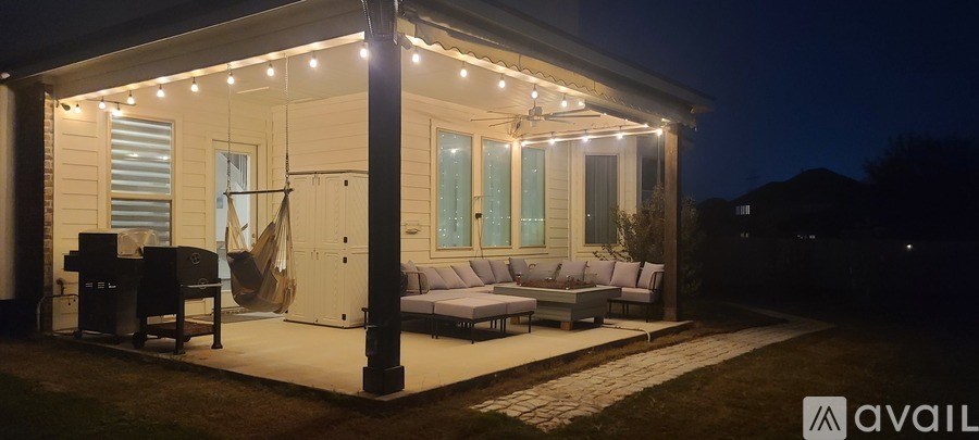 A white house with lights on the porch and a piano on the left.