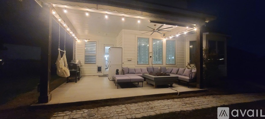 A patio area with a couch, table, and chairs is lit up at night.