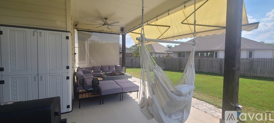A hammock is suspended between two poles on a covered patio.