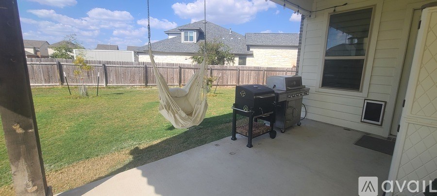 A patio with a hammock and a grill.