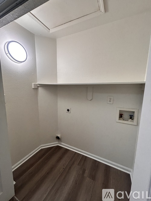 A small room with a round light on the wall and a shelf above the floor.