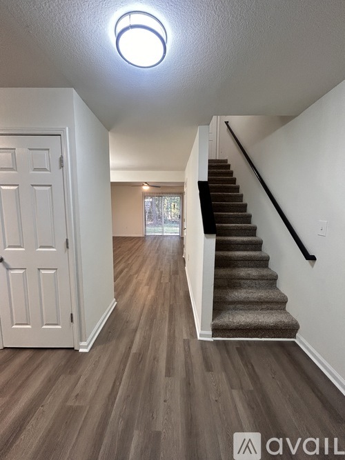 A hallway with a staircase and a white door.