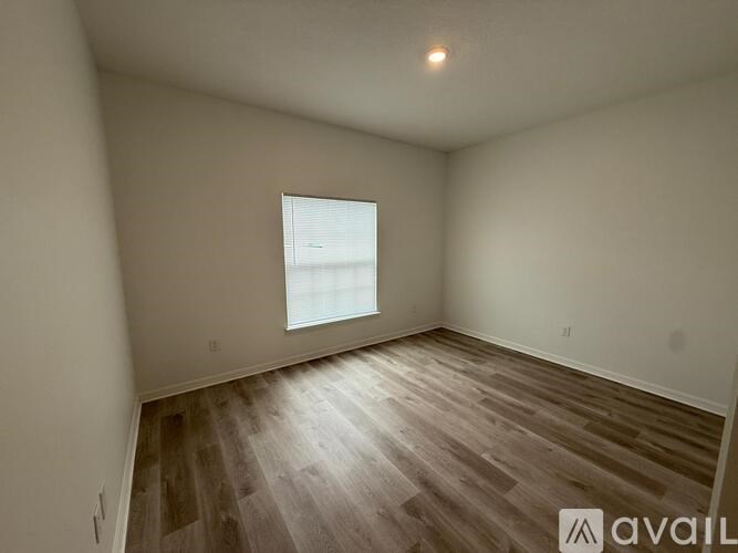 A room with wooden flooring and a window letting in light.