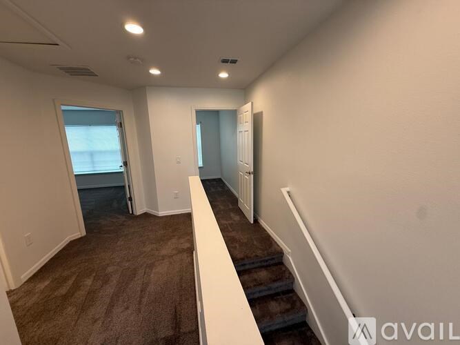 A room with a carpeted floor and a staircase leading to another room.