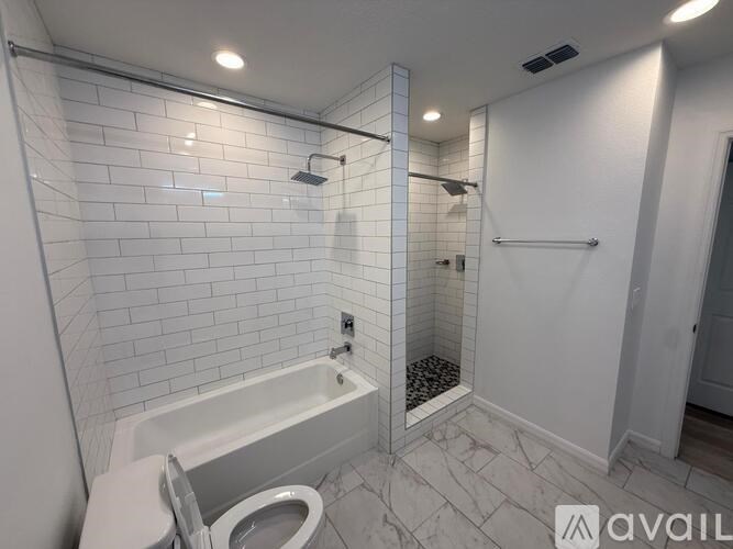 A white bathroom with a tub, toilet, and shower.