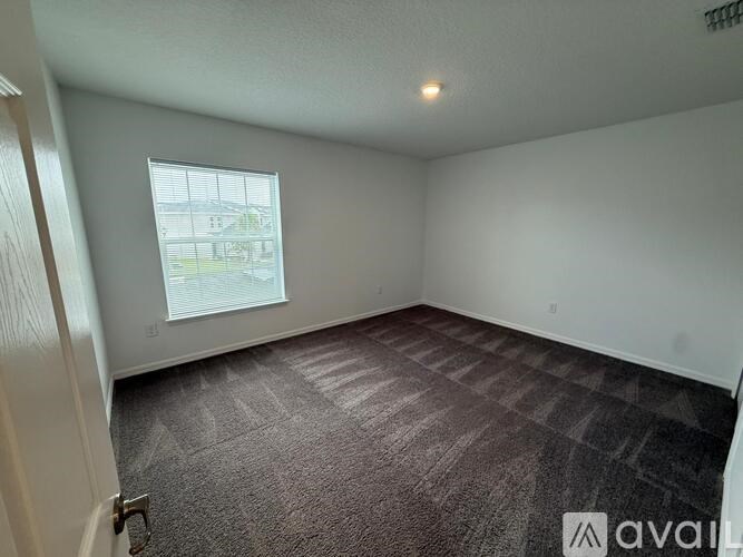 A room with a carpeted floor and a window letting in natural light.