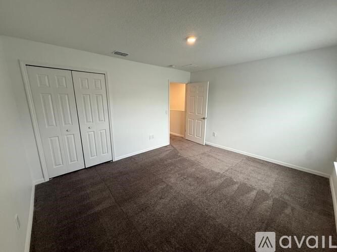 A room with a carpeted floor and two doors.