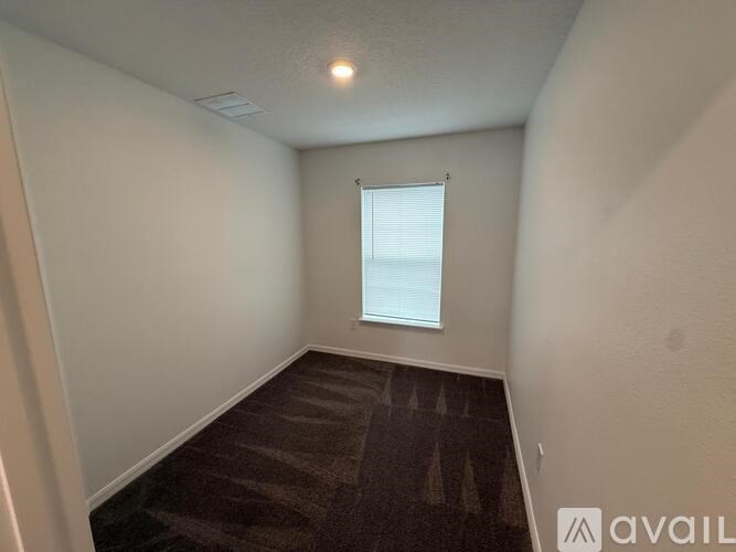 A room with a carpeted floor and a window with blinds.