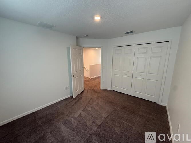 A room with a carpeted floor and two doors, one of which is open.