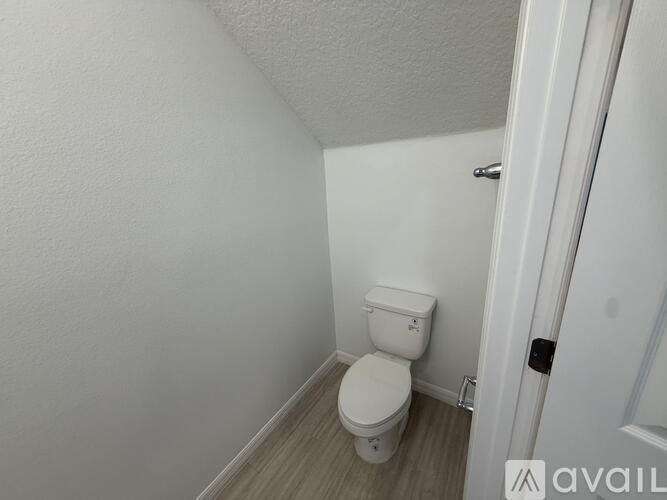 A white toilet in a small room with a door on the right.