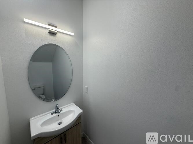 A bathroom with a sink, mirror and light.
