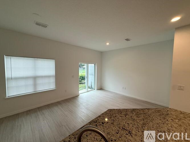 A spacious room with a marble table and a window with blinds.