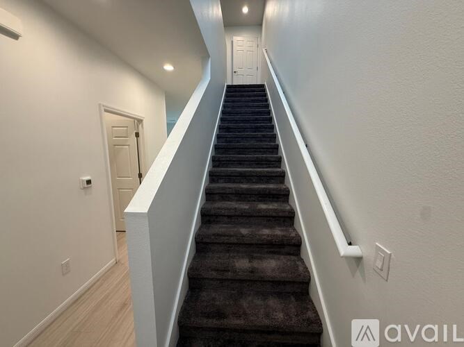 A staircase with a carpeted runner and white walls.
