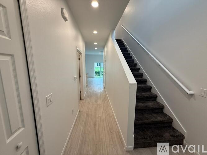 A hallway with a staircase on the right and a door at the end.