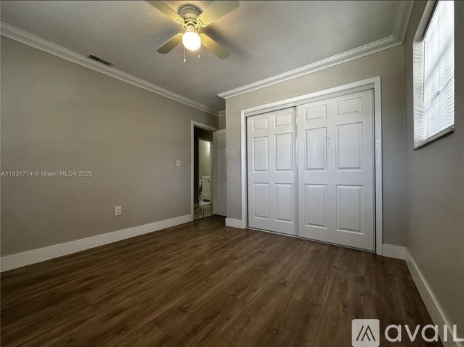 A room with a ceiling fan and a white door.