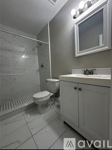 A white bathroom with a toilet, sink, and shower.
